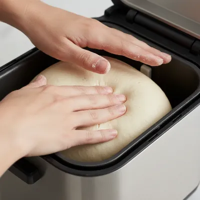 Hands checking the consistency of bread dough in a bread maker pan during the kneading cycle to prevent collapsed loaves